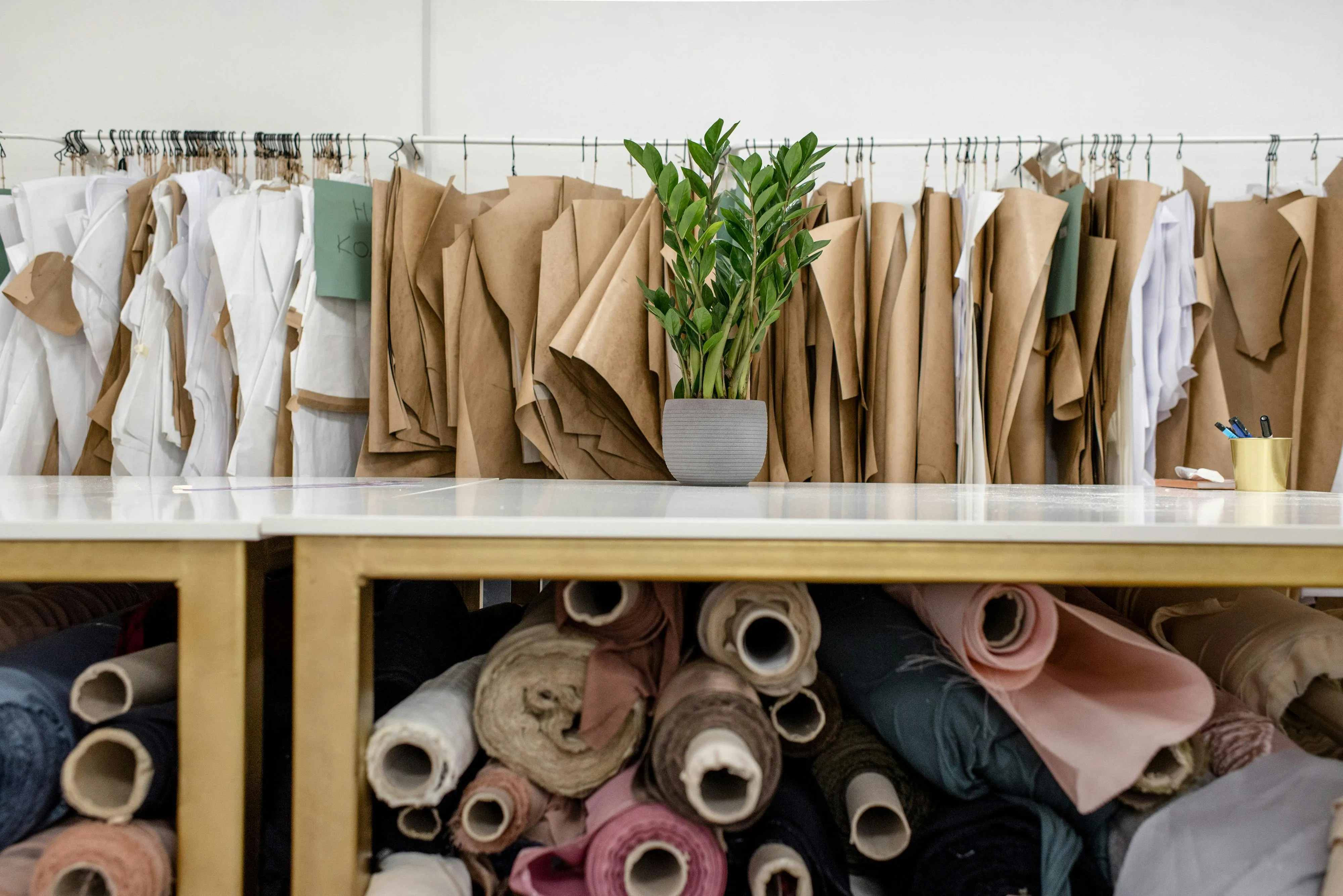 A shelf filled with rolls of fabric and a pot plant placed on top.